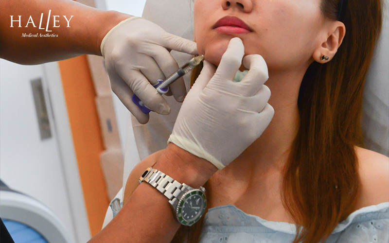 Doctor injecting dermal fillers on female patient's face