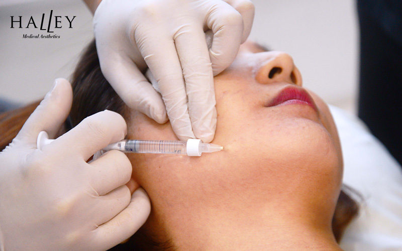 A doctor injecting a skin booster into a patient's cheek.
