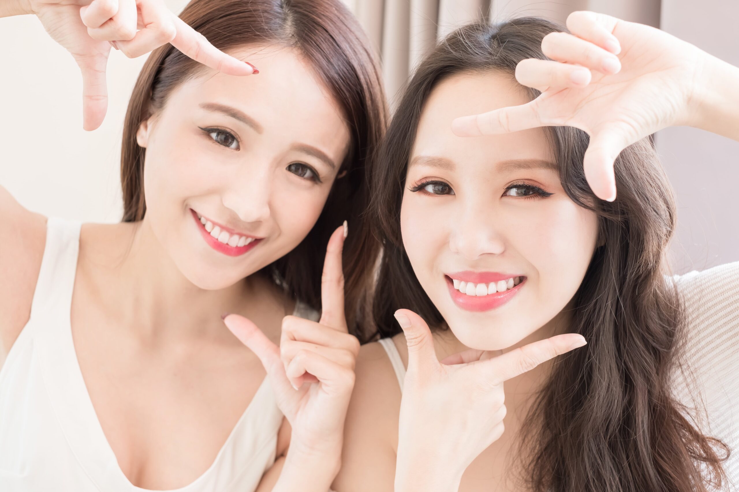 Two woman pointing their hands towards their eye